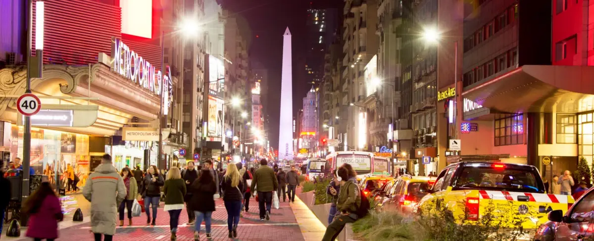Obelisco iluminado de noche con gente en la avenida 9 de Julio